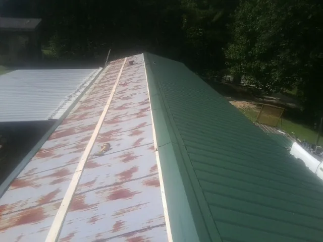 Old rusted panels beside newly installed green metal roofing — Wind Damage Roof Repair by Roofing Brothers in Newville