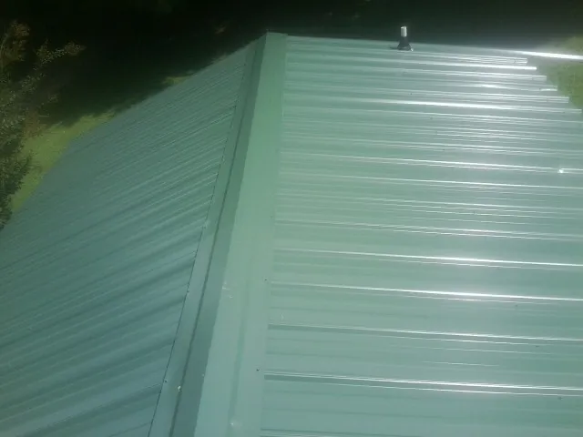 New green metal panels meeting at the ridge of a roof — Flat Roof Repair work by our crew in Newville