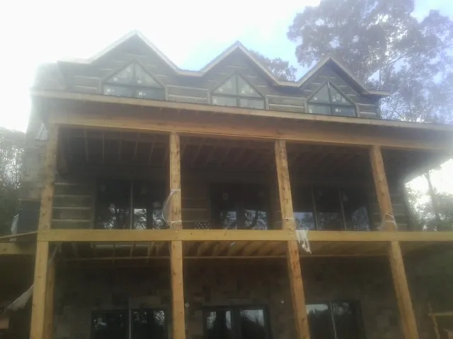 Dormers and porch framing on a large log home under construction — Roof Coating work by our crew in Newville
