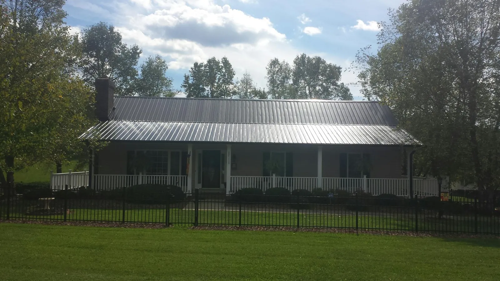 Gray metal roof on a brick ranch with a full width front porch — Gutter Guard Installation work by our crew in Newville