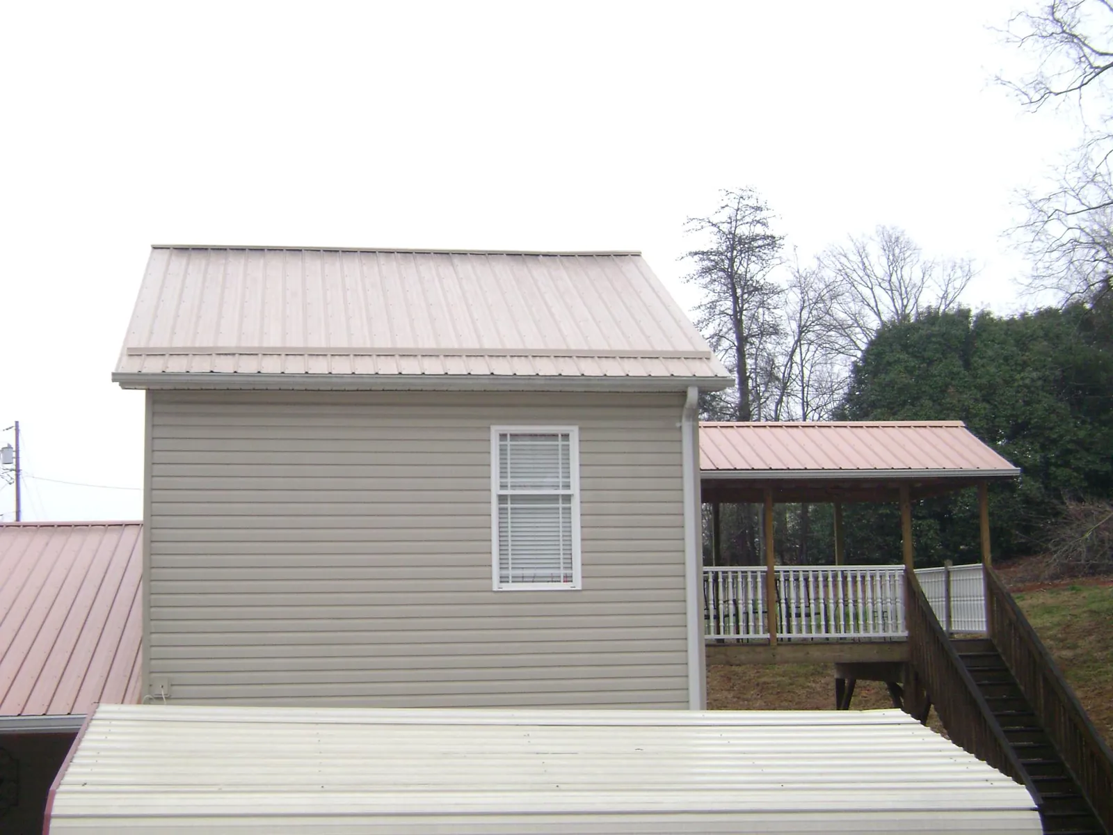 Tan metal roofs on a two story addition and attached porch, from a Roof Replacement job in Newville