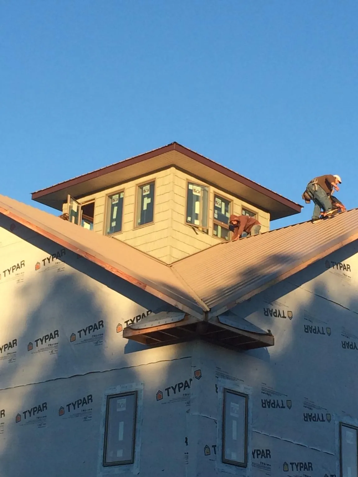 Roofers working around a rooftop cupola on a new metal roof at sunset — Roof Waterproofing in Newville by Roofing Brothers